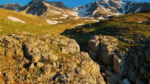 aerial View a rocky mountain range with snow on top and a valley in between