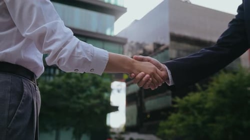 Asian Business Partners Engage in Handshake on Street