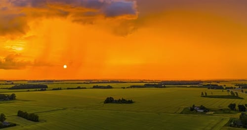 Glowing orange golden sunset over farmland crops - drone timelapse
