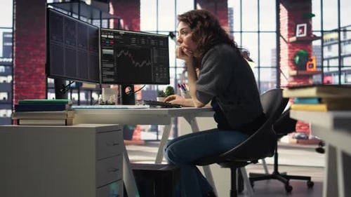 Woman Types At Desk With Two Monitors in Office