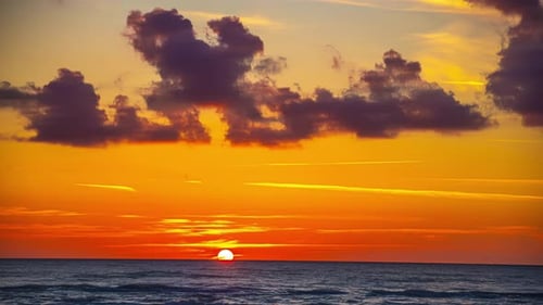 Sunset over ocean sea skyline, time-lapse end of day to night, moving clouds