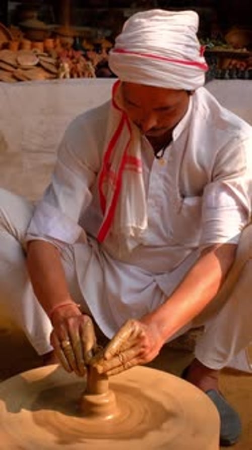Potier lançant le tour de potier et façonnant un pot en argile dans un atelier de poterie en Inde