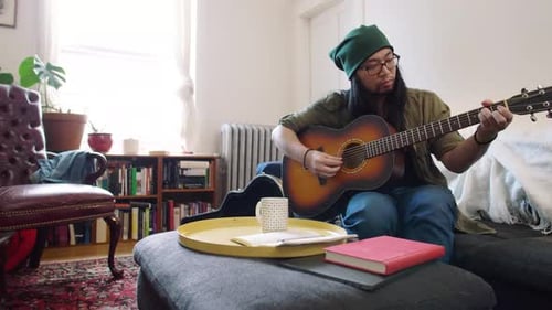 Young Man Playing Acoustic Guitar in Living Room