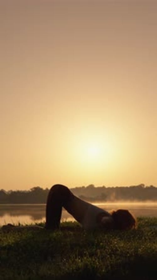 Slender Woman Practicing Yoga at Sunrise by Lake