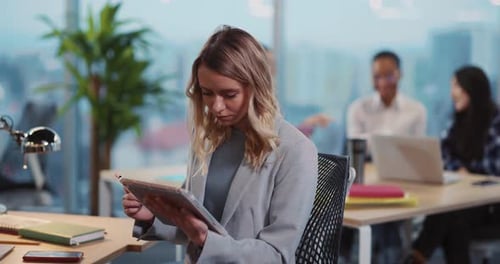 Businesswoman uses tablet at bright, modern office