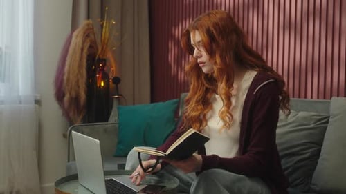 Woman Working from Home on Laptop, Writing in Notebook