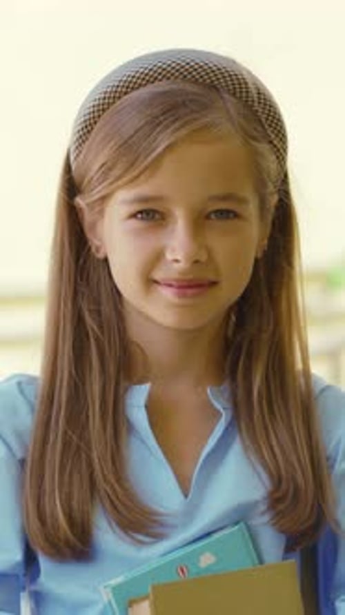 Young Girl Holding Books Smiles For Camera