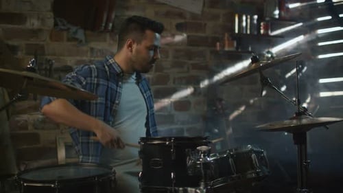 Drummer plays music while rehearsing a song in a home studio in a garage.