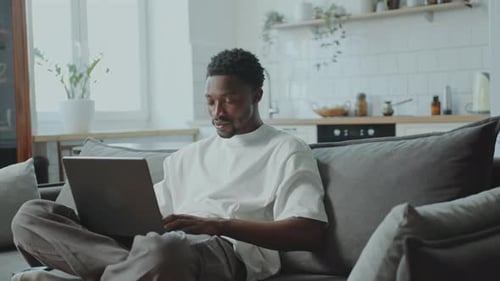 Man Working on Laptop While Sitting on Couch
