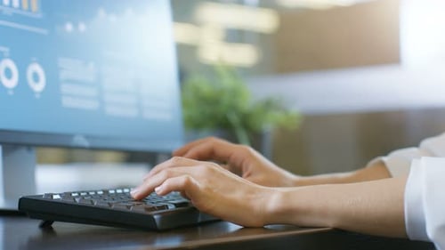 In den Händen der Bürofrau, die auf der Tastatur tippt, Monitor, auf dem Infografiken mit Statistiken angezeigt werden.