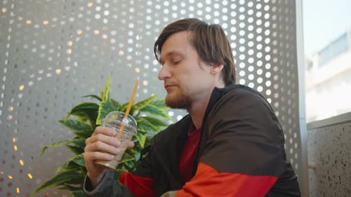 Young Adult Drinking Iced Coffee Inside