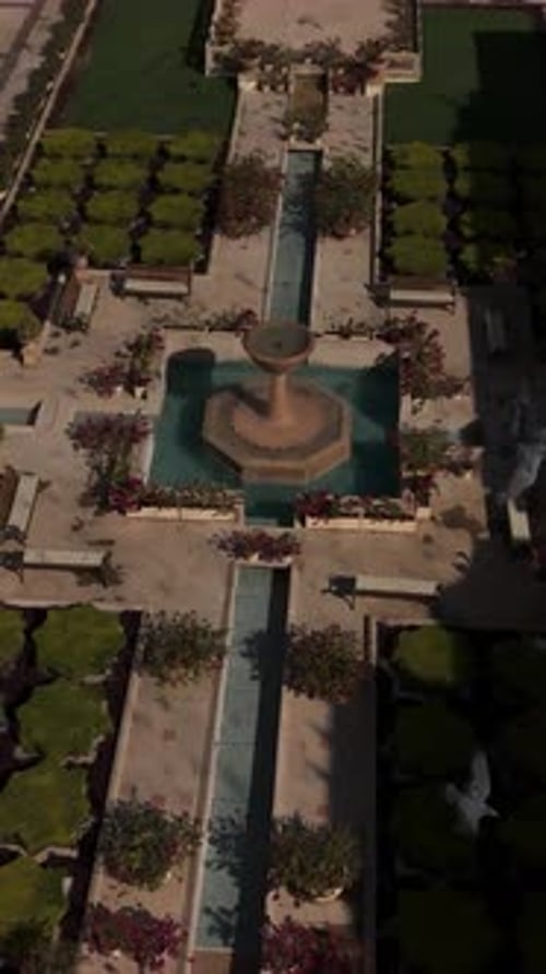 top-down perspective of an ornate courtyard garden featuring a central tiered fountain sitting