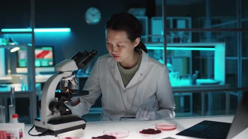 Woman Using Microscope for Scientific Research in Lab