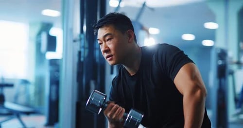 Muscular Asian Bodybuilder Man Training with Heavy Dumbbells Working Out Arm Muscles Blue Gym