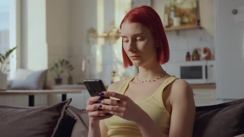 Woman Using Smartphone on Sofa at Home