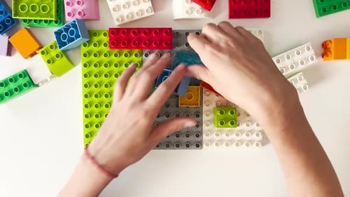Overhead shot of hands building with colorful blocks