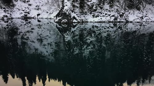 Aerial Reflection of Snowcovered Fir Trees in the Surface of a Mountain Lake
