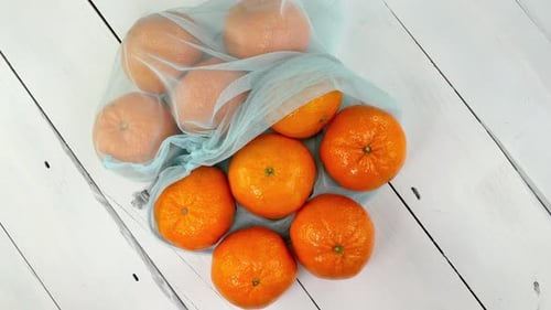 Mandarinas jugosas maduras en rejilla ecológica giran sobre fondo blanco