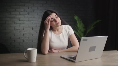 Thoughtful Woman Typing on Laptop at Desk