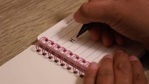 Woman's hand writes "happy new year!" word on the new book. New year concept. Close up
