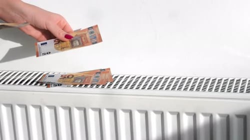 Hand Placing Euro Notes on Radiator