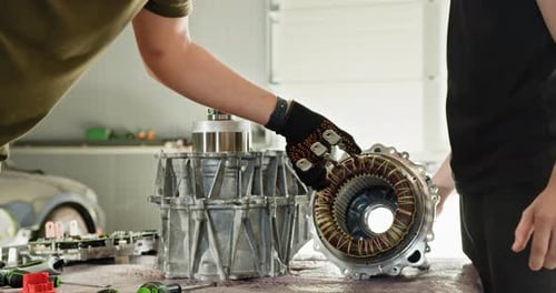 Mechanics Disassembling Electric Car Motor in Workshop