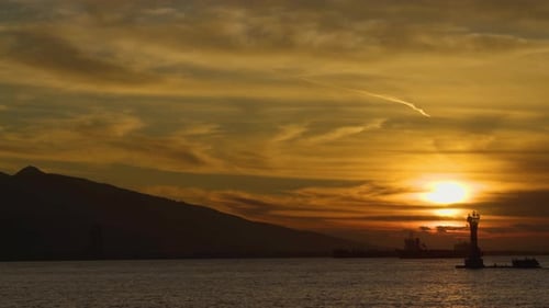 Goldener Sonnenuntergang über dem Meer mit Leuchtturm-Silhouette