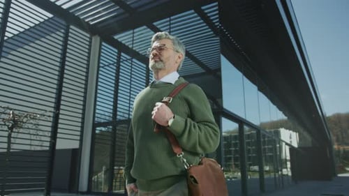 Stylish Man Walking Near a Modern Office Building