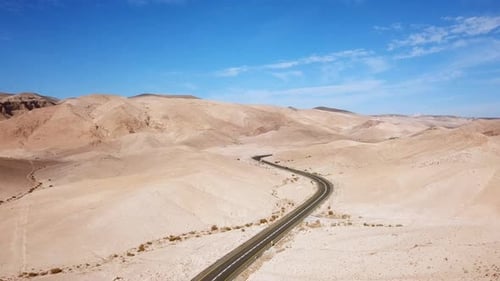 Empty desert road with mountains and blue sky in the background