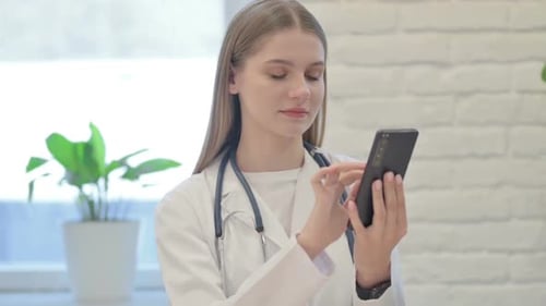Female Doctor Browsing Smartphone in Clinic