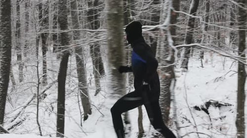 Side View of Sportsman Having Morning Run at Snowy Forest