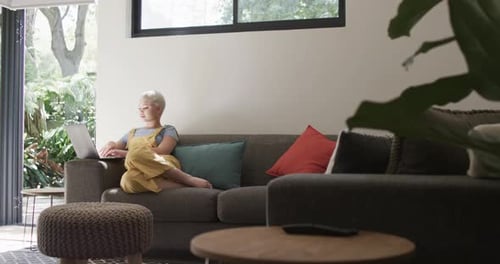 Young Adult Using Laptop on Couch at Home