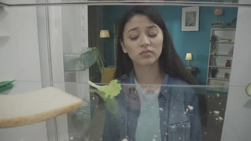 Young Woman Checking Empty Fridge Talking on Phone