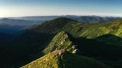 Drone flies over a tourist standing on top of a mountain. Summer hiking in the mountains.