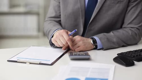 Businessman calculates finances at office workplace table using calculator