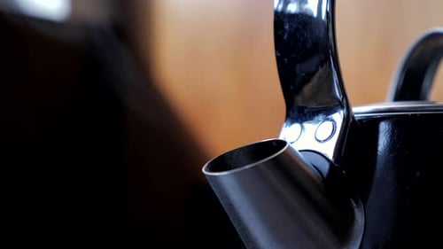 Nahaufnahme eines schwarzen Haushaltsküchenkessels, der langsam für eine Tasse Tee und Kaffee kocht