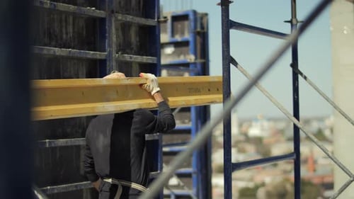 Construction Worker Carries Lumber on Building Site