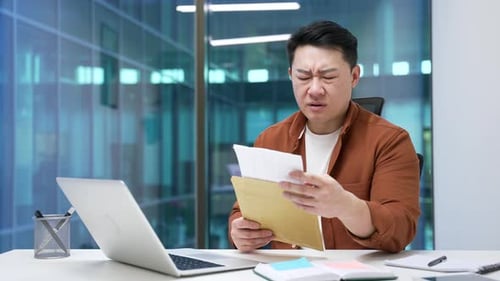 Confused Man Looking at Documents in Office