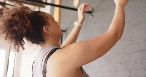 Reaching down, woman is gripping and thrusting purple medicine ball against brick wall for strength