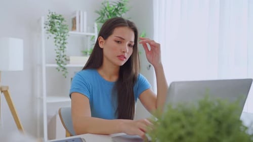 Woman Works on Laptop at Desk in Home Office