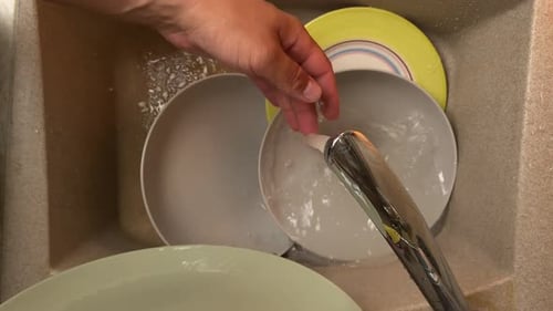 Hands Washing Dishes in a Sink with Sponge