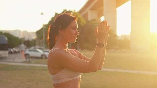 Confident Sporty Woman Stretching Arms at City Park During Sunny Day