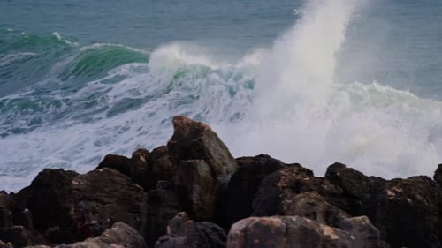 Waves Crashing Against Rocky Shoreline on Overcast Day