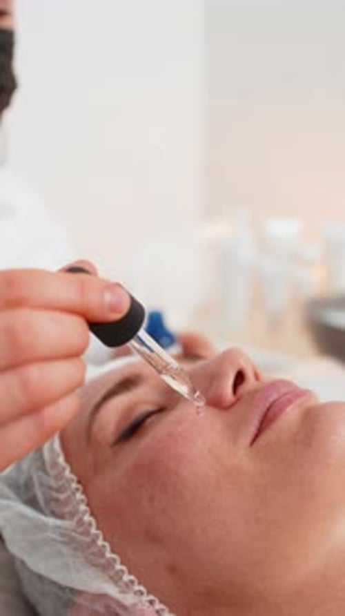 Woman Receiving Serum Application with Pipette By Beautician Cosmetology Clinic Skincare Procedure