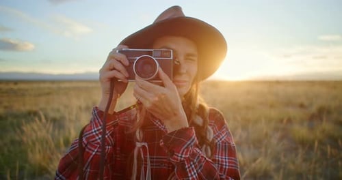 Photographer Taking Pictures with Vintage Camera in a Field at Sunset