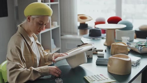 Woman Designs Fashion Hat at Studio Workspace