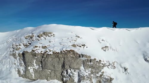 Solo hiker walking on the mountain ridge. Vast winter mountain landscape full of snow.