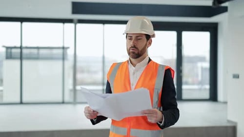 Professional Architect Reviews Blueprints in Modern Office Building