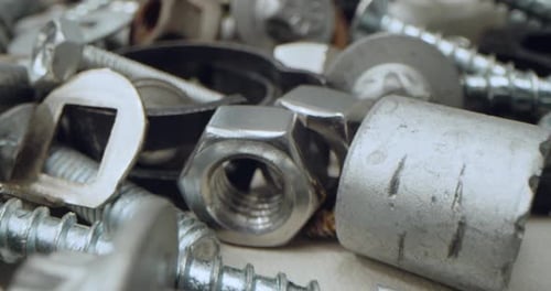 Nahaufnahme verschiedener Muttern, Schrauben und Befestigungselemente Ein verstreuter Haufen glänzender Metallteile, die in