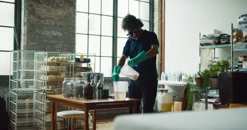 Jeune artisan masculin mélangeant des ingrédients de savon dans un atelier branché et lumineux